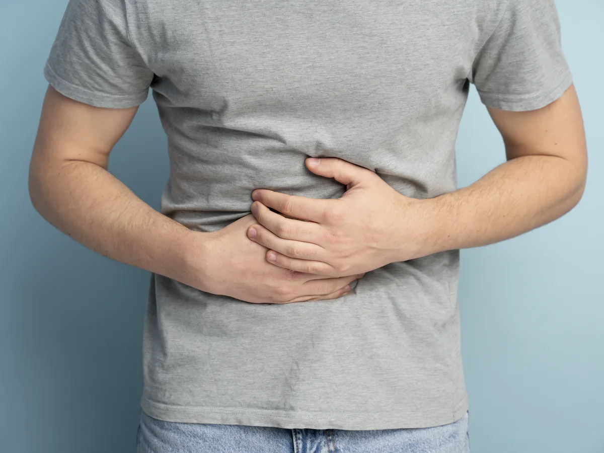 Persona llevándose las manos al abdomen por molestia en la zona del hígado