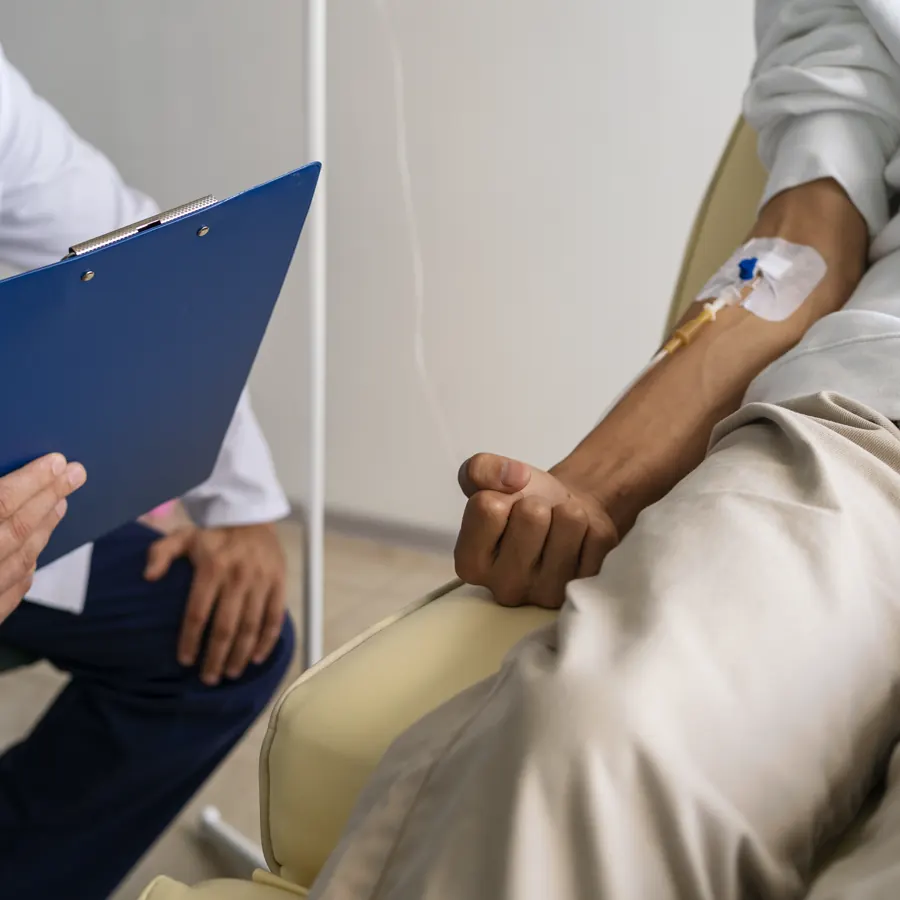 Paciente recibiendo sueroterapia intravenosa mientras el médico revisa su expediente