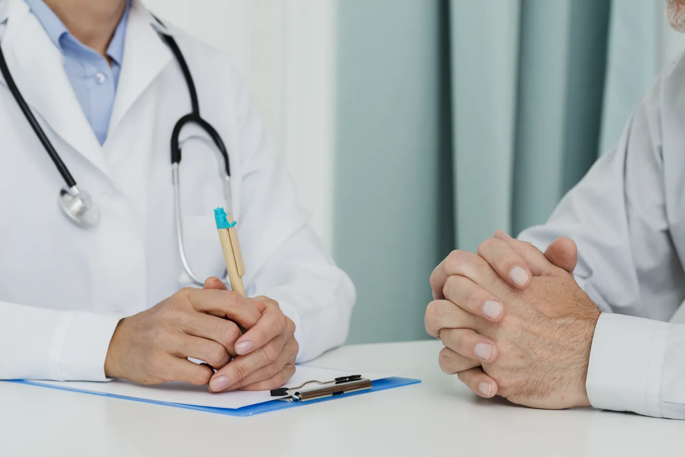 Médica y paciente frente a frente durante una consulta, con el expediente sobre la mesa